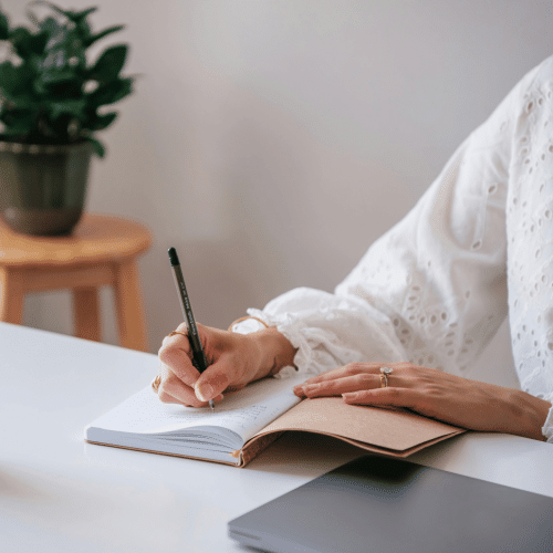 Woman writes in a notebook with a pen. Begin your personal story with this writing technique.